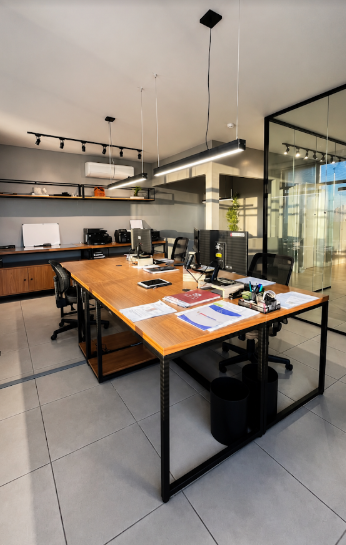 Sala de trabalho da CJ2 com mesa compartilhada e projetos técnicos